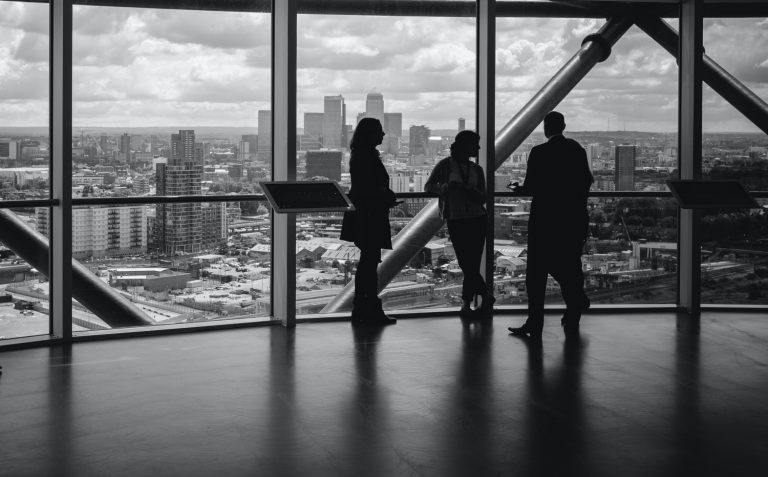 Personer i tomt lokale som ser ut over en by.